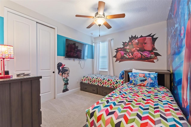 bedroom with ceiling fan, a textured ceiling, light carpet, and a closet