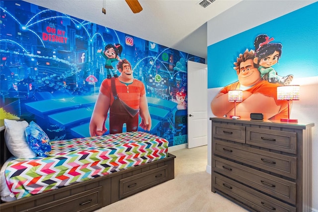 bedroom with ceiling fan, light colored carpet, and a textured ceiling