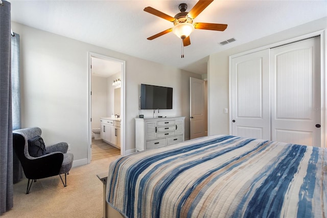 carpeted bedroom featuring ensuite bathroom, ceiling fan, and a closet