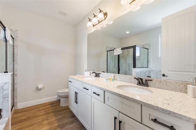 bathroom with hardwood / wood-style floors, walk in shower, vanity, and toilet