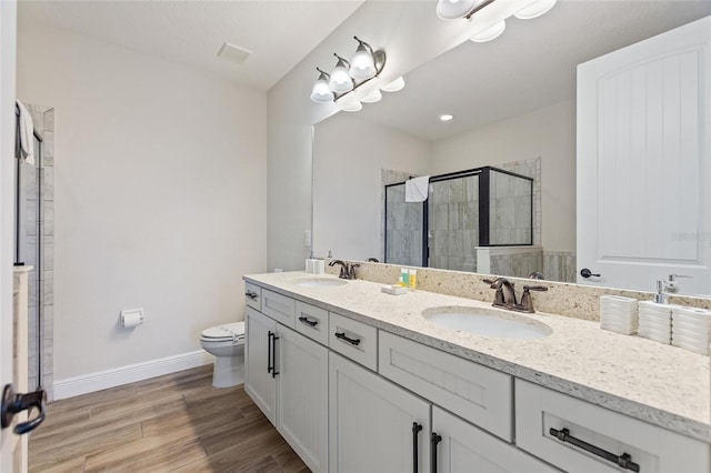 bathroom with wood-type flooring, toilet, vanity, and a shower with shower door