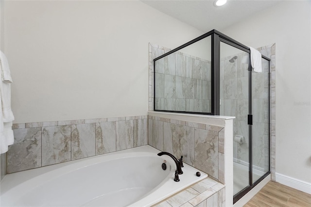 bathroom featuring shower with separate bathtub and wood-type flooring