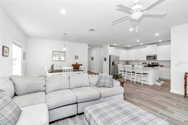 living room with ceiling fan and light wood-type flooring