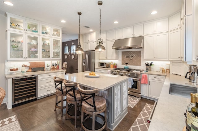 kitchen featuring stainless steel appliances, white cabinetry, dark hardwood / wood-style floors, hanging light fixtures, and beverage cooler