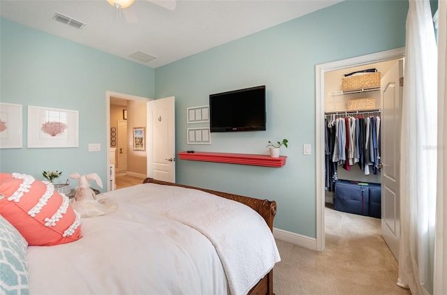 bedroom with ceiling fan, light carpet, a closet, and a spacious closet