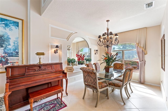 tiled dining space featuring an inviting chandelier, a textured ceiling, and a wealth of natural light