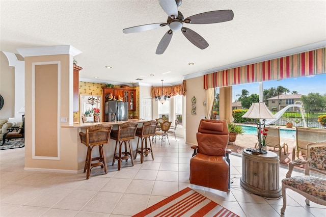 tiled living room featuring ceiling fan, ornamental molding, and a textured ceiling