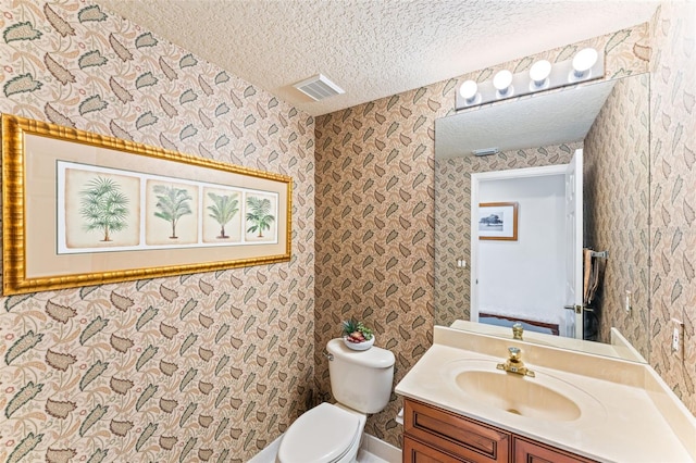 bathroom with vanity, toilet, and a textured ceiling