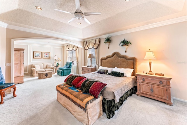 carpeted bedroom with ceiling fan, ornamental molding, a tray ceiling, and a textured ceiling