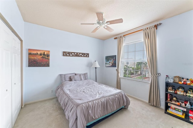 bedroom featuring ceiling fan, light colored carpet, a textured ceiling, and a closet