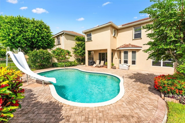 view of swimming pool with a patio and a water slide