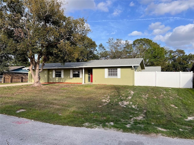 ranch-style home with a front yard, fence, and stucco siding