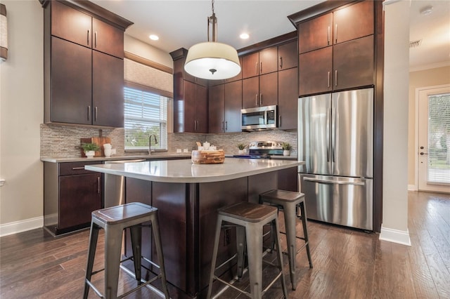 kitchen featuring stainless steel appliances, tasteful backsplash, dark hardwood / wood-style floors, dark brown cabinets, and pendant lighting