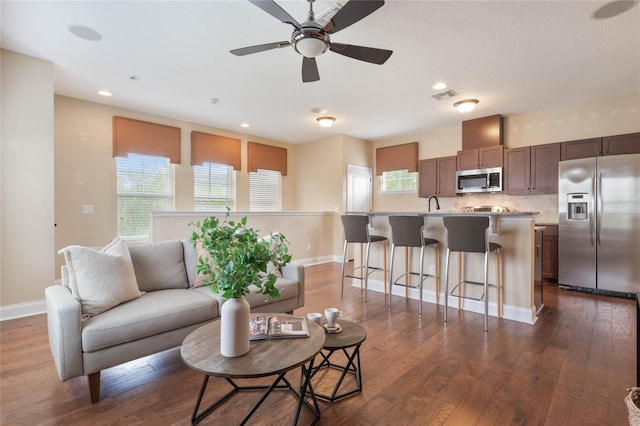 living room featuring ceiling fan, a healthy amount of sunlight, sink, and dark hardwood / wood-style flooring