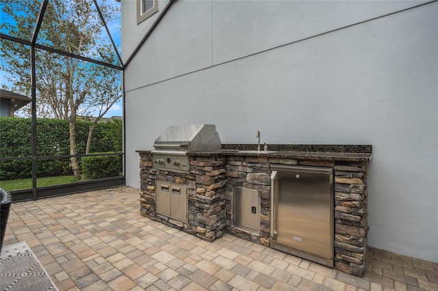 view of patio / terrace with an outdoor kitchen, glass enclosure, sink, and grilling area