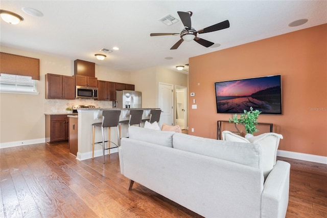 living room featuring dark wood-type flooring and ceiling fan