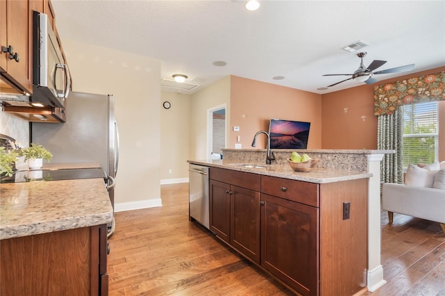 kitchen featuring light wood-type flooring, appliances with stainless steel finishes, sink, and light stone counters