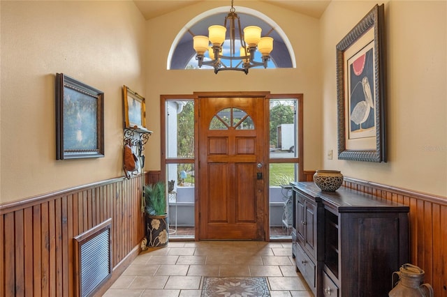 entryway with light tile patterned floors, an inviting chandelier, and vaulted ceiling