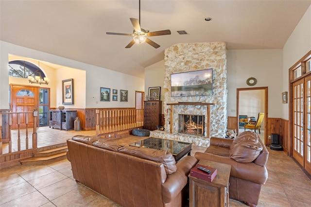 living room featuring wood walls, light tile patterned flooring, ceiling fan, high vaulted ceiling, and a fireplace