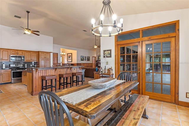 tiled dining area featuring ceiling fan with notable chandelier and vaulted ceiling