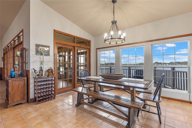 tiled dining area with high vaulted ceiling, french doors, and a notable chandelier