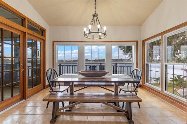 dining room featuring light tile patterned flooring, a wealth of natural light, a chandelier, and vaulted ceiling