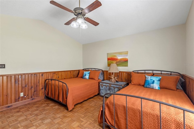 bedroom featuring wood walls, lofted ceiling, light parquet flooring, and ceiling fan