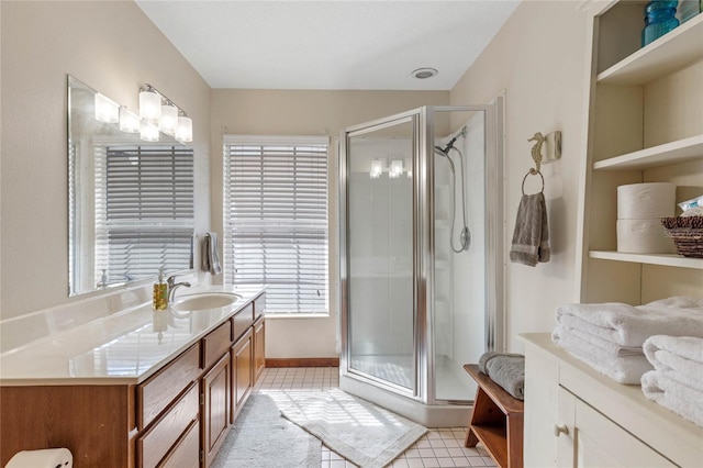 bathroom with a wealth of natural light, vanity, tile patterned floors, and a shower with door