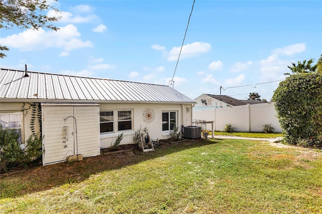 rear view of house featuring central AC unit and a yard