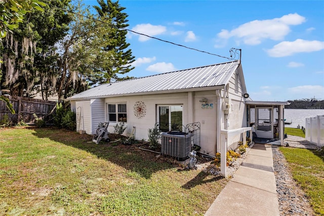 view of front of property featuring central air condition unit, a front yard, and a water view