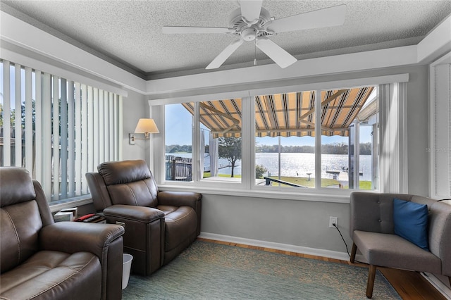 living area featuring hardwood / wood-style floors, a water view, a textured ceiling, and ceiling fan