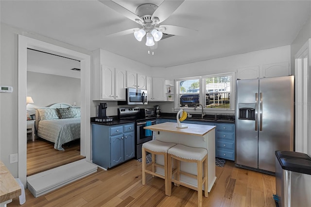 kitchen with white cabinetry, appliances with stainless steel finishes, blue cabinetry, and light wood-type flooring