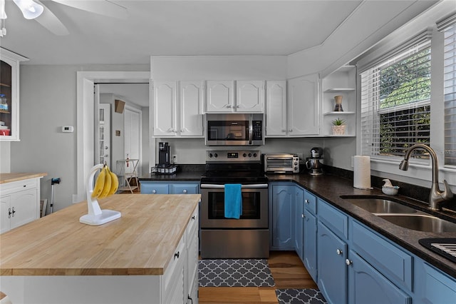 kitchen featuring wooden counters, appliances with stainless steel finishes, sink, dark wood-type flooring, and blue cabinets