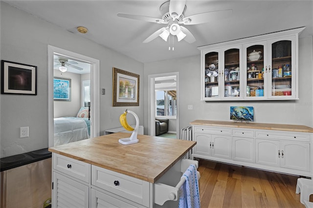 kitchen with white cabinets, butcher block countertops, wood-type flooring, and ceiling fan