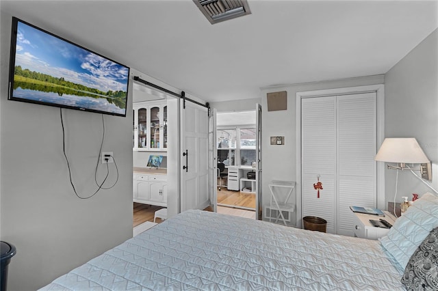 bedroom featuring light wood-type flooring and a barn door