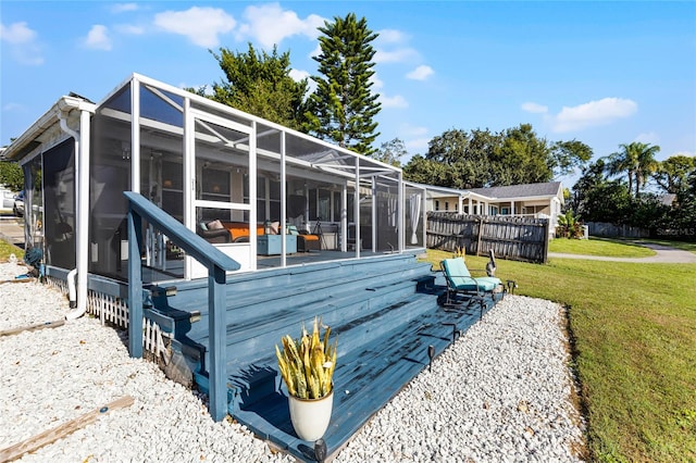 rear view of property featuring a sunroom, glass enclosure, and a yard