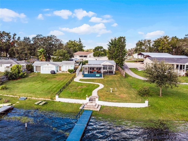 back of property featuring a lawn, a sunroom, and a water view