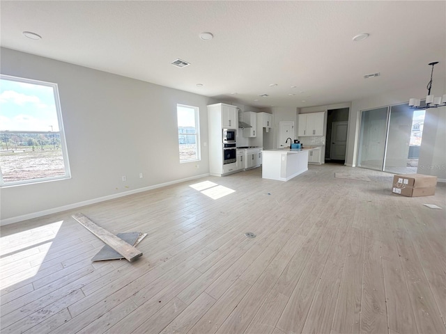 unfurnished living room with sink and light wood-type flooring