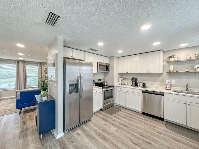 3310 W 63rd St W, Bradenton, FL 34209 - kitchen with appliances with stainless steel finishes, recessed lighting, light wood-style flooring, a textured ceiling, and white cabinetry