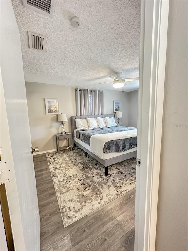 bedroom with hardwood / wood-style floors, a textured ceiling, and ceiling fan