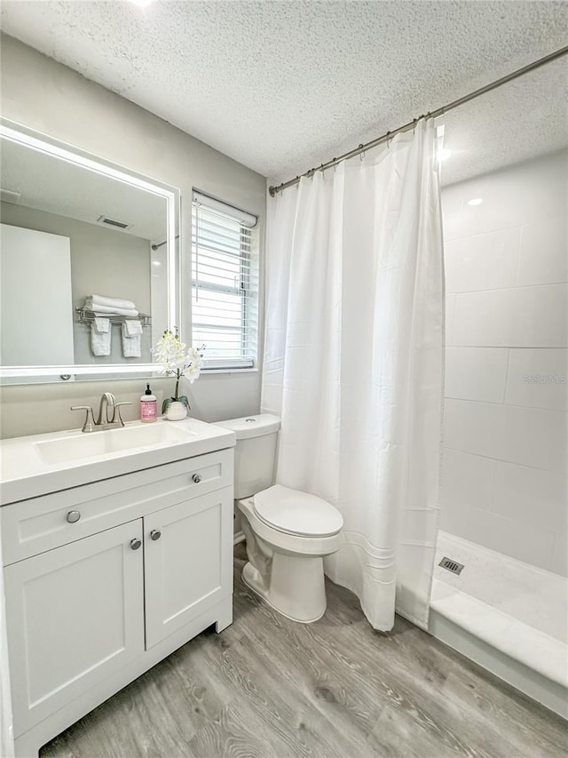 bathroom with curtained shower, hardwood / wood-style floors, a textured ceiling, toilet, and vanity