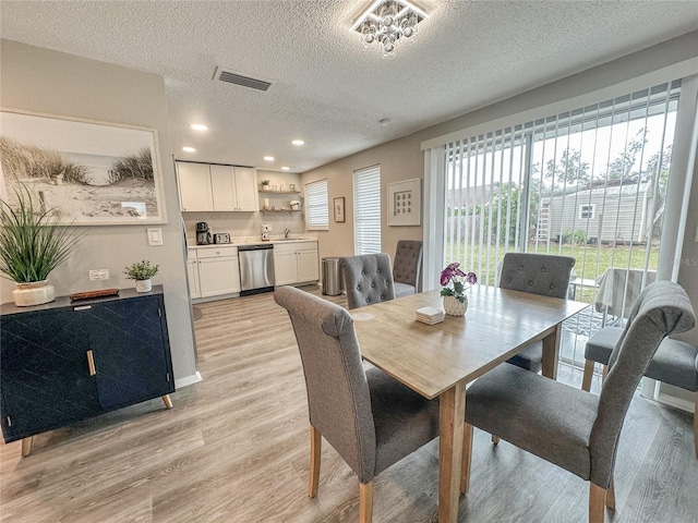 dining room featuring a textured ceiling, light hardwood / wood-style floors, and sink