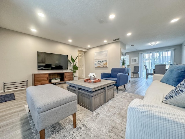 living room featuring a textured ceiling and light hardwood / wood-style floors