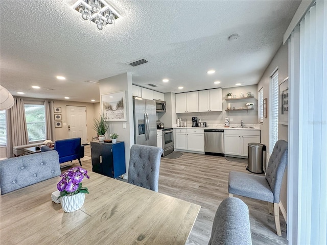 dining space featuring sink, light hardwood / wood-style floors, and a textured ceiling