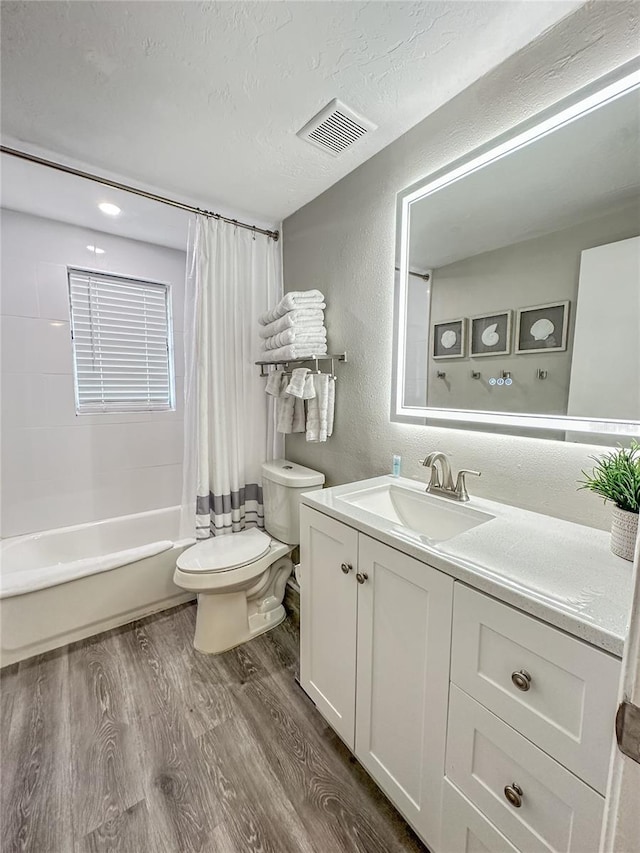 full bathroom featuring vanity, shower / bath combination with curtain, toilet, a textured ceiling, and wood-type flooring