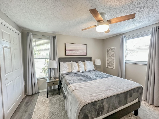 bedroom featuring ceiling fan, a closet, wood-type flooring, and a textured ceiling