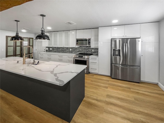 kitchen featuring white cabinets, light hardwood / wood-style flooring, hanging light fixtures, sink, and appliances with stainless steel finishes