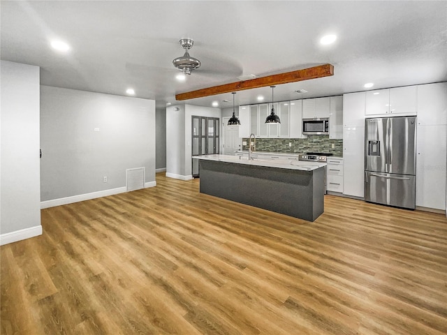 kitchen with stainless steel appliances, pendant lighting, a kitchen island with sink, white cabinetry, and light wood-type flooring