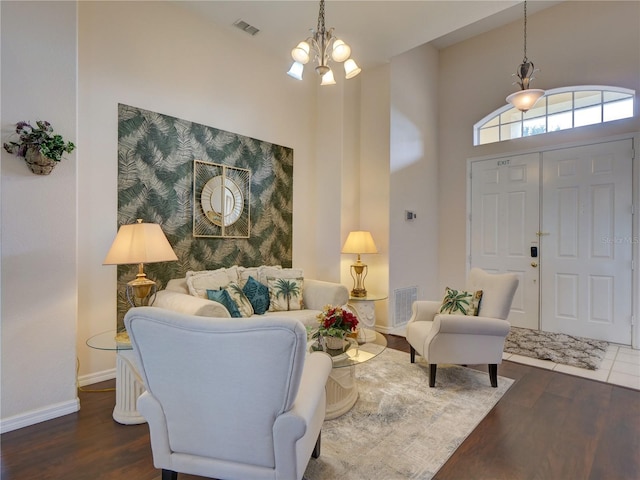 living room with dark wood-type flooring, an inviting chandelier, and a towering ceiling