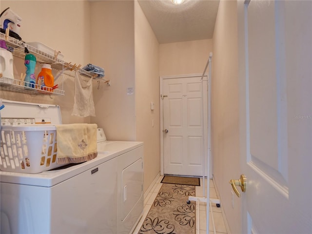 laundry area with washing machine and clothes dryer, light tile patterned floors, and a textured ceiling